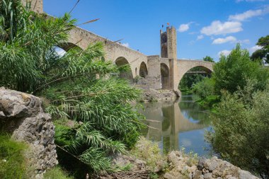 Girona, İspanya - 7 Temmuz 2024: Besalu, Katalonya 'daki Fluvia Nehri üzerindeki Ortaçağ Pont Vell köprüsünün yansımaları