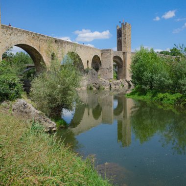 Girona, İspanya - 7 Temmuz 2024: Besalu, Katalonya 'daki Fluvia Nehri üzerindeki Ortaçağ Pont Vell köprüsünün yansımaları