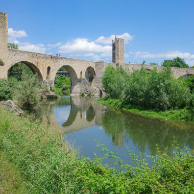 Girona, İspanya - 7 Temmuz 2024: Besalu, Katalonya 'daki Fluvia Nehri üzerindeki Ortaçağ Pont Vell köprüsünün yansımaları