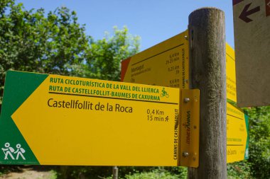 Girona, İspanya - 7 Temmuz 2024: Castellfollit de la Roca, Katalonya 'ya giden yolda yürüyüş yapanlara ve bisikletçilere yol gösteren işaret direği