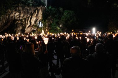 Lourdes, France - 1 Nov, 2024: Pilgrims attend a mass service at the Our Lady of Lourdes statue at Massabielle clipart