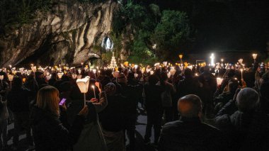 Lourdes, France - 1 Nov, 2024: Pilgrims attend a mass service at the Our Lady of Lourdes statue at Massabielle clipart