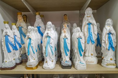 Lourdes, France - 1 Nov, 2024: Virgin Mary Statues, Candles and other Catholic memorabilia on sale in a gift shop in Lourdes clipart