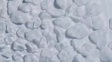 Temiz dalgalı suyun altında beyaz çakıl taşları