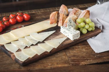 Üzümlü peynir tabağı, fındık ve bal ahşap kesim tahtasında 