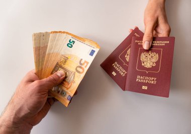 Masada pasaport ve para (euro) taşıyan erkek ve kadın elleri var. Rusya 'dan diğer ülkelere göç, Rus vatandaşlığı veya pasaportu satın alma veya satma kavramı 
