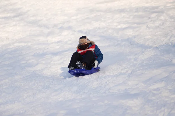 stock image Uman, Ukraine, - January 9, 2017. A small young boy rides down a hill on a sled. Winter season. Sunny weather.