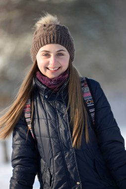 Karlı kış parkında gülümseyen mutlu genç kadın. Güneşli bir hava. Kış mevsimi.