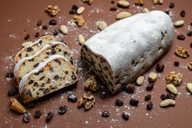 Geleneksel kek tozlu pudra şekerli kurutulmuş meyve ve fındıklı kahverengi arka planda.