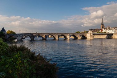 Maastricht, Hollanda - 17 Eylül 2024: Kentin liman kıyısındaki eski taş köprünün manzarası