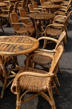 Açık bir verandada, kafe ya da restoran oturma alanına özgü sayısız boş rattan sandalye ve küçük masalar düzenlenmiştir.