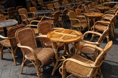 Açık bir verandada, kafe ya da restoran oturma alanına özgü sayısız boş rattan sandalye ve küçük masalar düzenlenmiştir.