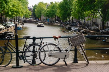 Amsterdam Kanalı 'na bakan bir köprüye parketmiş iki bisiklet.