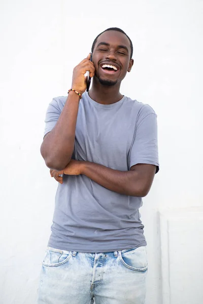 携帯電話で話しているハンサムな若いアフリカ人男性の肖像画と白壁に対して笑顔 — ストック写真