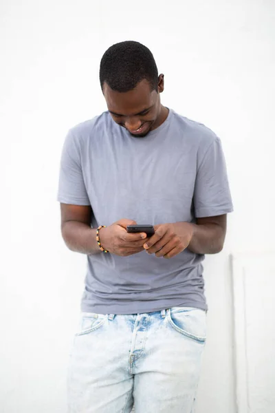 白い背景を持つ携帯電話を使用して笑顔の若いアフリカ人男性の肖像画 — ストック写真