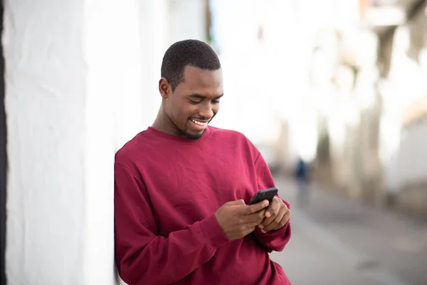 Portret Przystojnego Młodego Afrykanina Smsującego Przez Telefon Komórkowy Opierającego Się — Zdjęcie stockowe