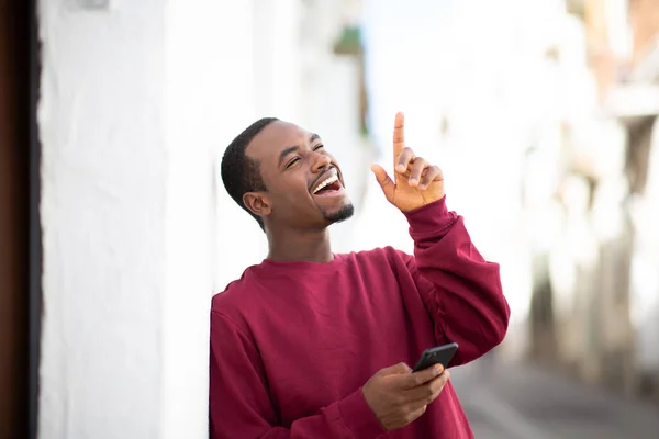 Portrét Vzrušeného Mladého Afrického Američana Držícího Mobilní Telefon Ukazujícího Nahoru — Stock fotografie
