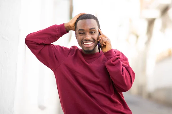 壁にもたれて携帯電話で屋外で話している黒人の笑顔の肖像画 — ストック写真