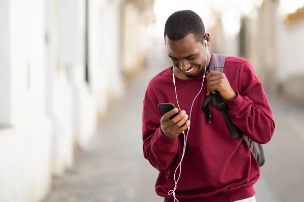 Portret Wesoły Młody Czarny Facet Telefonem Komórkowym Słuchanie Muzyki Słuchawkami — Zdjęcie stockowe