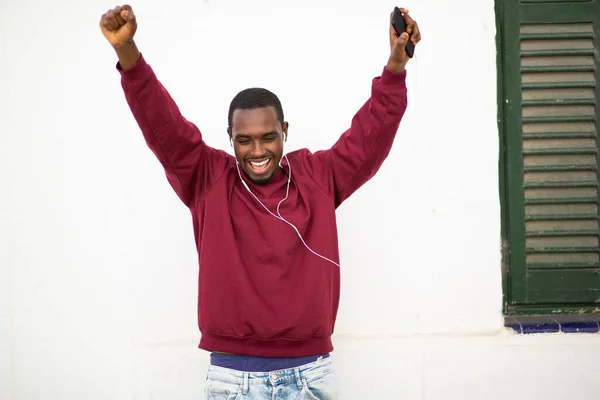 一个兴奋的年轻非洲男人的画像 他喜欢用耳机听音乐 喜欢在外面靠墙跳舞 — 图库照片