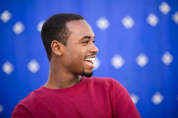 年轻快乐的黑人男子在蓝色背景下 望着远方 微笑着的特写 — 图库照片