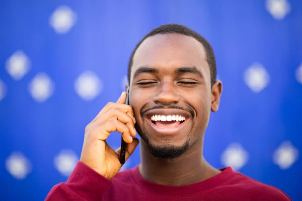 Zbliżenie Portret Szczęśliwy Młody Czarny Człowiek Mówi Przez Telefon Niebieskim — Zdjęcie stockowe
