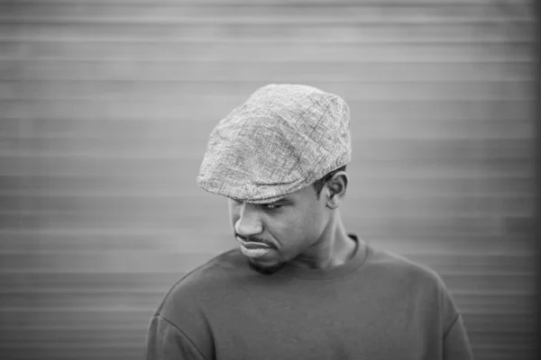 stock image Close up black and white portrait of stylish young black guy with cap looking down and thinking