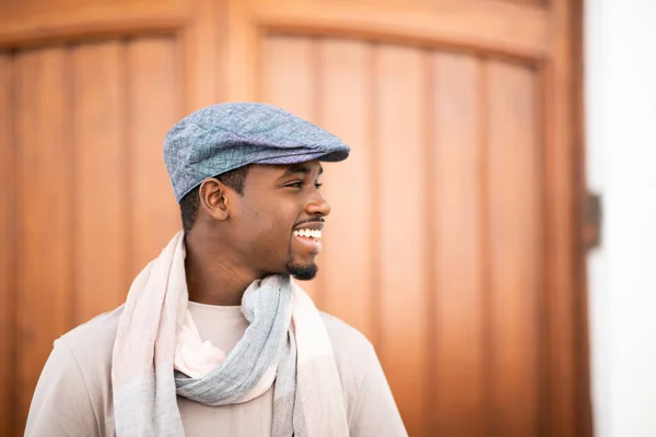 带着帽子和围巾的快乐的年轻非洲男子的侧面画像 目光移开 微笑着 — 图库照片