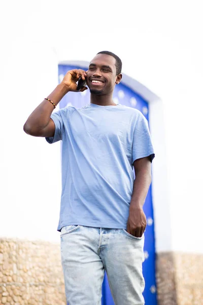 携帯電話で話して外を歩くハンサムな若いアフリカ人男性の肖像画 — ストック写真