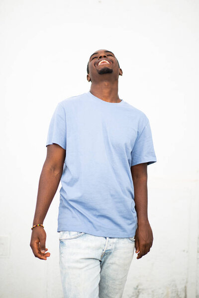 Portrait of cheerful young african american man smiling against white wall