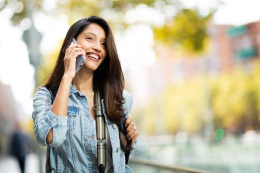 Cep telefonuyla konuşan mutlu genç kadının portresini kapat. 