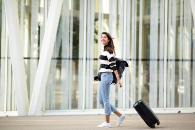 Tam vücut portresi. Mutlu seyahat eden kadın. Elinde bavulla şehirde yürüyor.