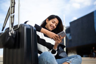 Cep telefonuyla oturan mutlu seyahat eden kadın portresi 