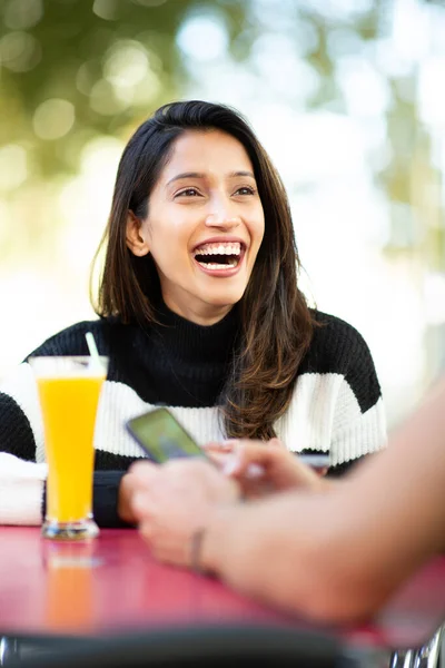 与朋友坐在咖啡桌旁笑着的快乐的年轻女人 — 图库照片