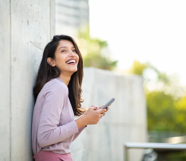 Sidoporträtt Glad Ung Kvinna Lutar Sig Mot Väggen Håller Mobiltelefon — Stockfoto