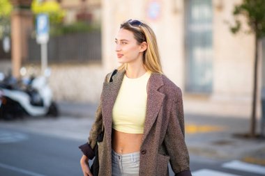 Gülümseyen kadın şehir caddesini geçerken başka tarafa bakıyor.