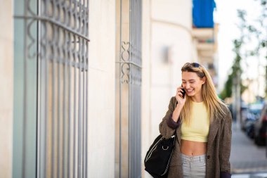 Moda kadını şehir dışında cep telefonuyla konuşuyor.