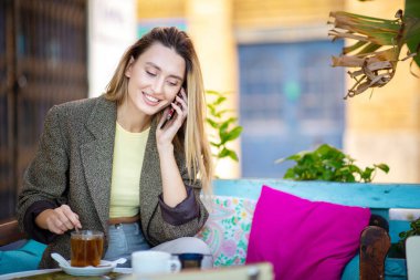 Açık kafede cep telefonuyla konuşan güzel bir kadın.
