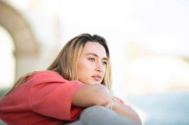 Açık havada eğilip düşünen genç bir kadının portresi. 