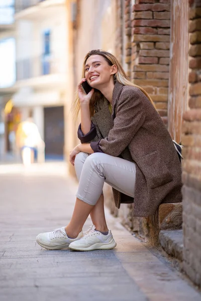 Šťastná Stylová Žena Mluví Telefonu Zatímco Sedí Venku — Stock fotografie