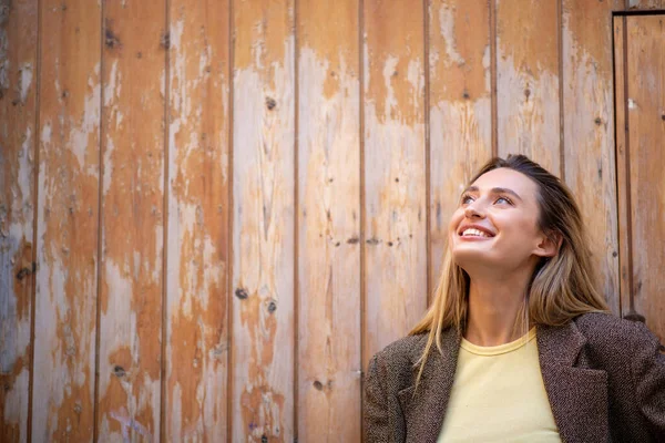 Usmívající Mladá Žena Kabátě Vzhlíží Proti Dřevěným Dveřím — Stock fotografie