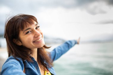 Sahilde tatildeyken selfie çeken mutlu genç bir kadının portresi.