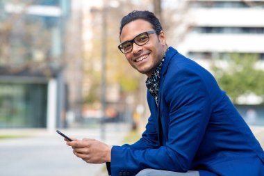 Dışarıda cep telefonuyla oturan yakışıklı siyahi işadamının portresi.