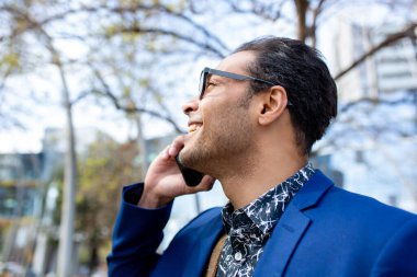 Şehirde cep telefonuyla konuşan mutlu, genç, Afro-Amerikan iş adamının profil fotoğrafını çek.