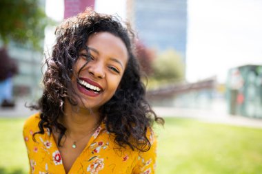 Dışarıda gülen neşeli Afrikalı genç bir kadının yakın portresi.