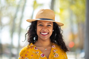 Çekici, şapkalı, dışarıda gülümseyen Latin kadının portresini yakından çek.
