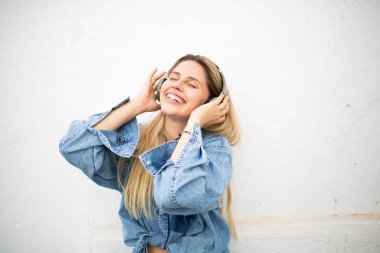 Beyaz duvara gülümseyen kulaklıklı güzel Latin kadının portresi.