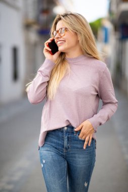 Şehirde cep telefonuyla konuşan çekici genç bir kadının portresi.