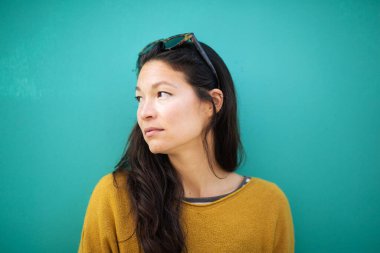 Asyalı genç bir kadının portresini yakından çek. Başka tarafa bak ve yeşil arka plan üzerinde düşün.