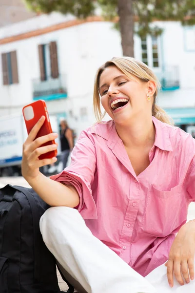 明るい若い女性の肖像は 市内に座っている間に携帯電話でビデオ通話を行う — ストック写真